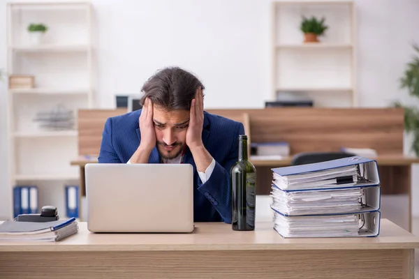 Junge alkoholabhängige männliche Angestellte arbeitet im Büro — Stockfoto