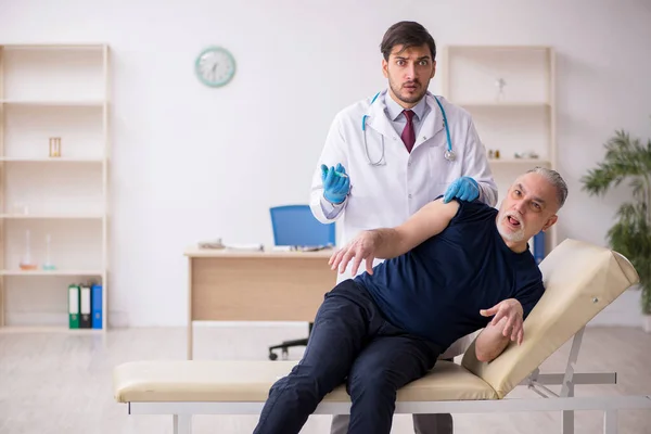 Alte männliche Patientin besucht jungen männlichen Arzt im Impfpass — Stockfoto