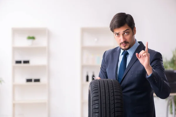 Mladý muž prodává pneumatiky v kanceláři — Stock fotografie