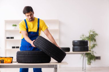 Atölyede lastiği olan genç bir erkek tamirci.