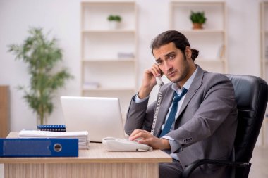 Ofisteki aşırı işten memnun olmayan genç bir erkek işçi.