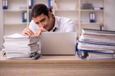 Genç bir erkek çalışan ve ofiste bir sürü iş var.