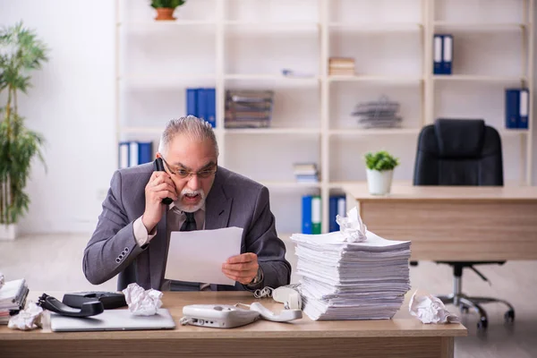 Oude mannelijke werknemer die op de werkplek werkt — Stockfoto