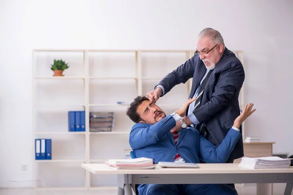 Velho chefe e jovem empregado masculino no conceito de bullying — Fotografia de Stock