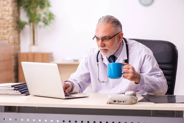 Verouderde mannelijke arts die koffie drinkt in de kliniek — Stockfoto