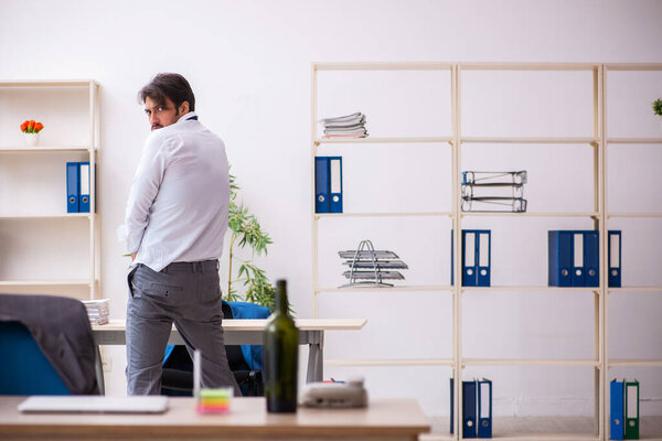 Young alcohol addicted employee sitting in the office