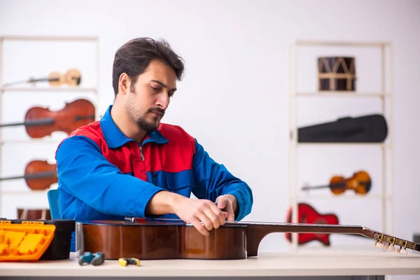 Young male repairman repairing musical instruments at workplace — Stock Photo, Image