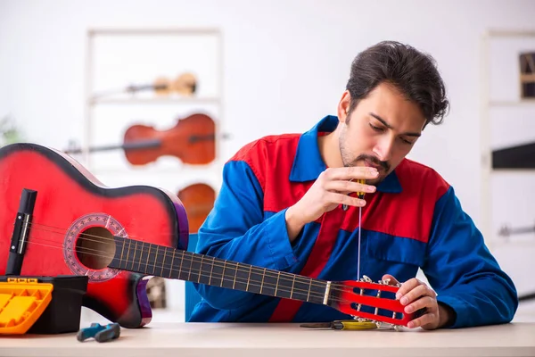 Genç erkek tamirci işyerinde müzik aletlerini tamir ediyor. — Stok fotoğraf