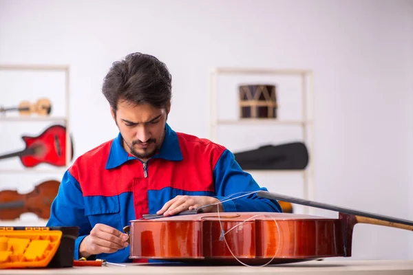 Jonge mannelijke reparateur die muziekinstrumenten repareert op het werk — Stockfoto