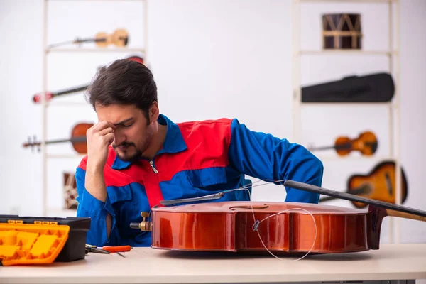 Hombre joven reparador reparando instrumentos musicales en el lugar de trabajo —  Fotos de Stock