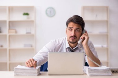 Ofisteki aşırı işten memnun olmayan genç bir erkek işçi.