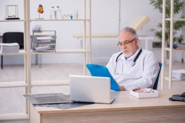 Klinikte çalışan yaşlı erkek doktor.