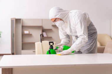 Genç erkek müteahhit evde haşere kontrolü yapıyor.