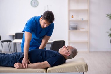 Yaşlı adam genç erkek doktoru ziyaret ediyor.