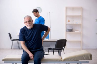 Yaşlı adam genç erkek doktoru ziyaret ediyor.