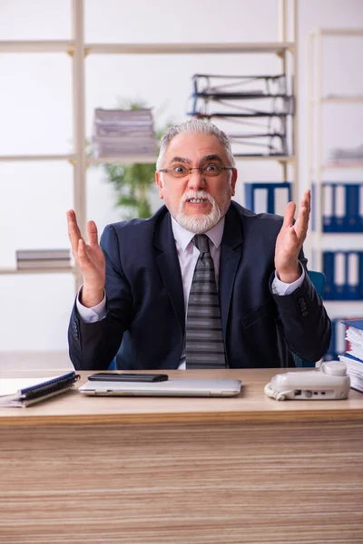 Старий чоловік-працівник незадоволений надмірною роботою в офісі — стокове фото