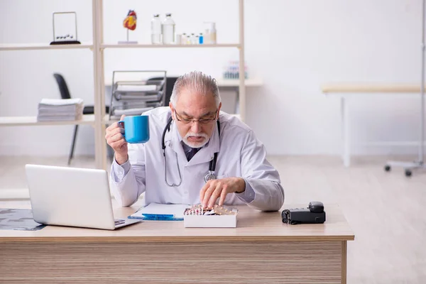 Klinikte çalışan yaşlı erkek doktor. — Stok fotoğraf