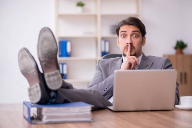 Genç çekici erkek çalışan işyerinde oturuyor.