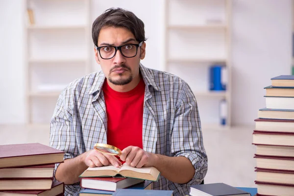 Jovem estudante do sexo masculino e muitos livros em sala de aula — Fotografia de Stock