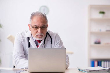 Klinikte çalışan yaşlı erkek doktor.
