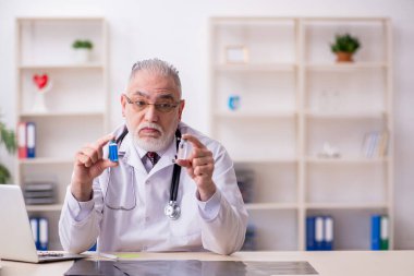 Klinikte çalışan yaşlı erkek doktor.