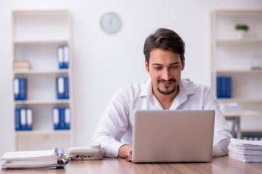 Genç bir erkek çalışan ve ofiste çok fazla iş var.