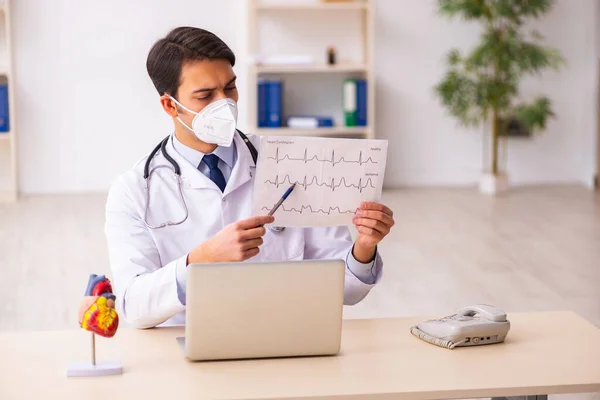 Genç erkek doktor kardiyolog pand sırasında klinikte çalışıyor. — Stok fotoğraf