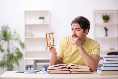 Genç erkek öğrenci zaman yönetimi konsepti sınavlarına hazırlanıyor.