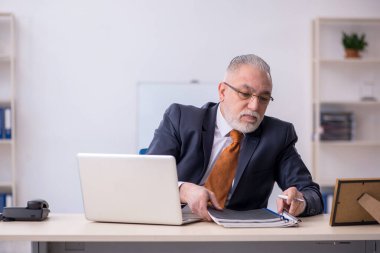 Ofiste çalışan yaşlı bir erkek.