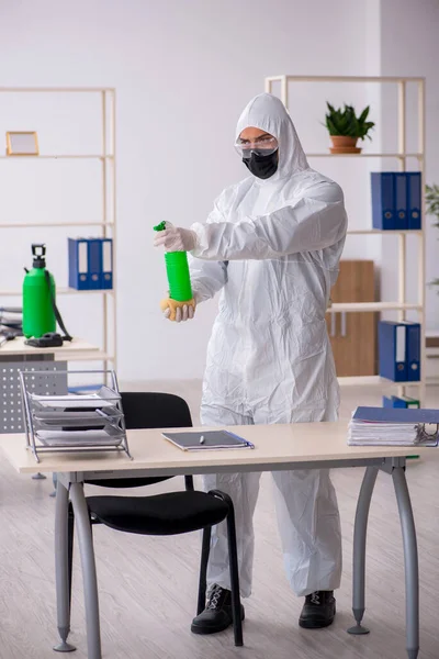 Jovem empreiteiro masculino desinfetando escritório durante pandemia — Fotografia de Stock