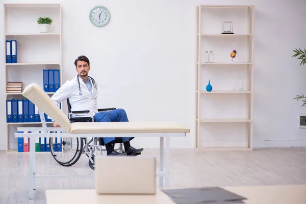 Klinikte çalışan tekerlekli sandalyedeki genç erkek doktor. — Stok fotoğraf