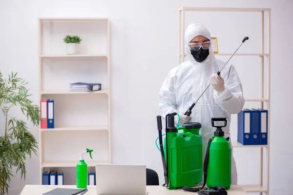 Contratista masculino joven desinfectando oficina durante pandemia —  Fotos de Stock