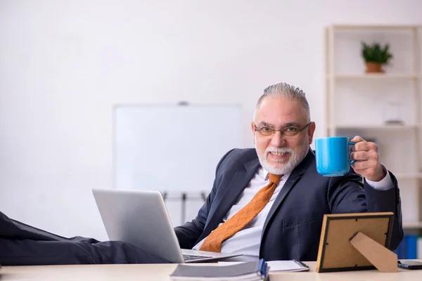 Gammal manlig anställd dricker kaffe under rasten — Stockfoto