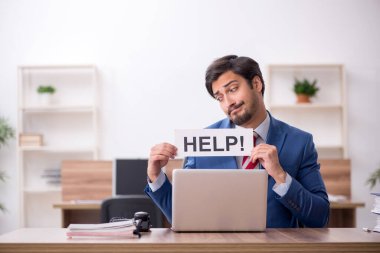 Genç erkek çalışan işyerinde oturuyor.