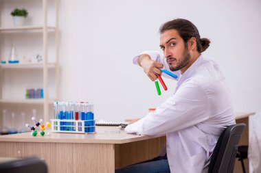 Sınıftaki masada oturan genç bir kimyager.