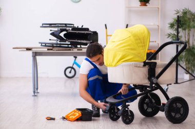 Genç erkek tamirci perambulator tamir ediyor.