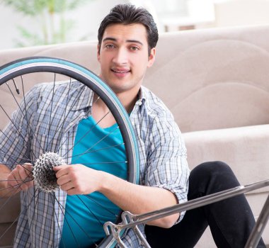 Evde bisiklet tamir eden genç bir adam.