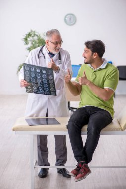 Genç adam yaşlı erkek doktor radyoloğu ziyaret ediyor.