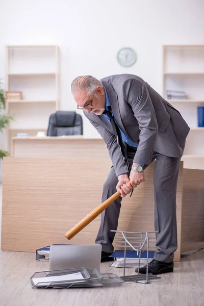 Old male employee holding baseball bat in the office — Stock Photo, Image