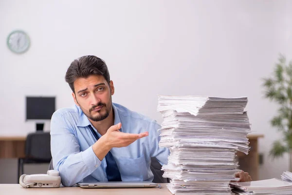 Young male employee and too much work in the office — Stock Photo, Image