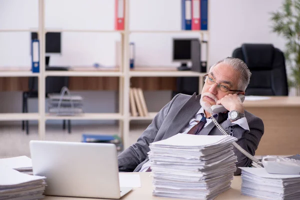 Oude mannelijke werknemer ongelukkig met overmatig werk in het kantoor — Stockfoto