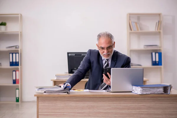 Пожилой бизнесмен, сидящий в офисе — стоковое фото
