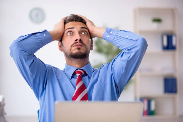 Joven empleado masculino descontento con el trabajo excesivo en la oficina —  Fotos de Stock