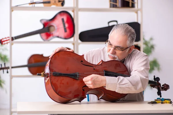 Oude mannelijke reparateur repareert muziekinstrumenten op het werk — Stockfoto