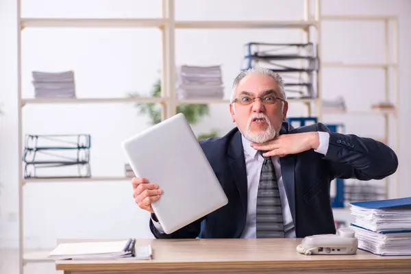 Oude mannelijke werknemer ongelukkig met overmatig werk in het kantoor — Stockfoto