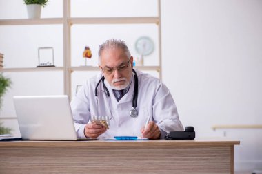 Klinikte çalışan yaşlı erkek doktor.