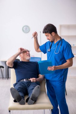 Yaşlı adam genç erkek doktoru ziyaret ediyor.