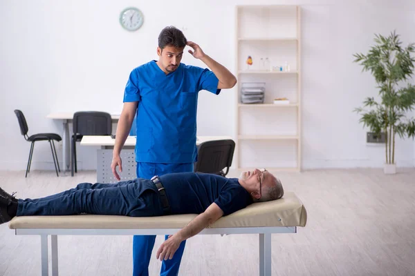 Old man visiting young male doctor — Stock Photo, Image