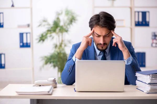 Ung manlig anställd och för mycket arbete på kontoret — Stockfoto