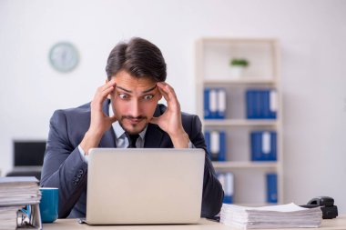 Genç erkek çalışan işyerinde oturuyor.